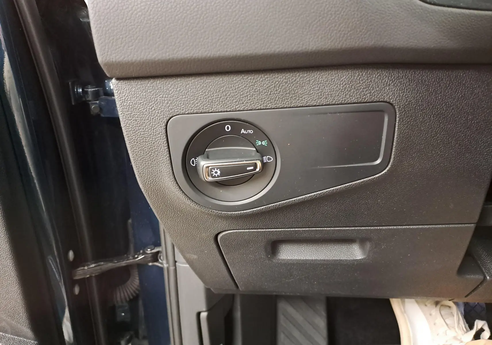 Gros plan sur le bouton de commande des phares côté gauche du tableau de bord du Volkswagen Tiguan Nightshade Blue 2023.