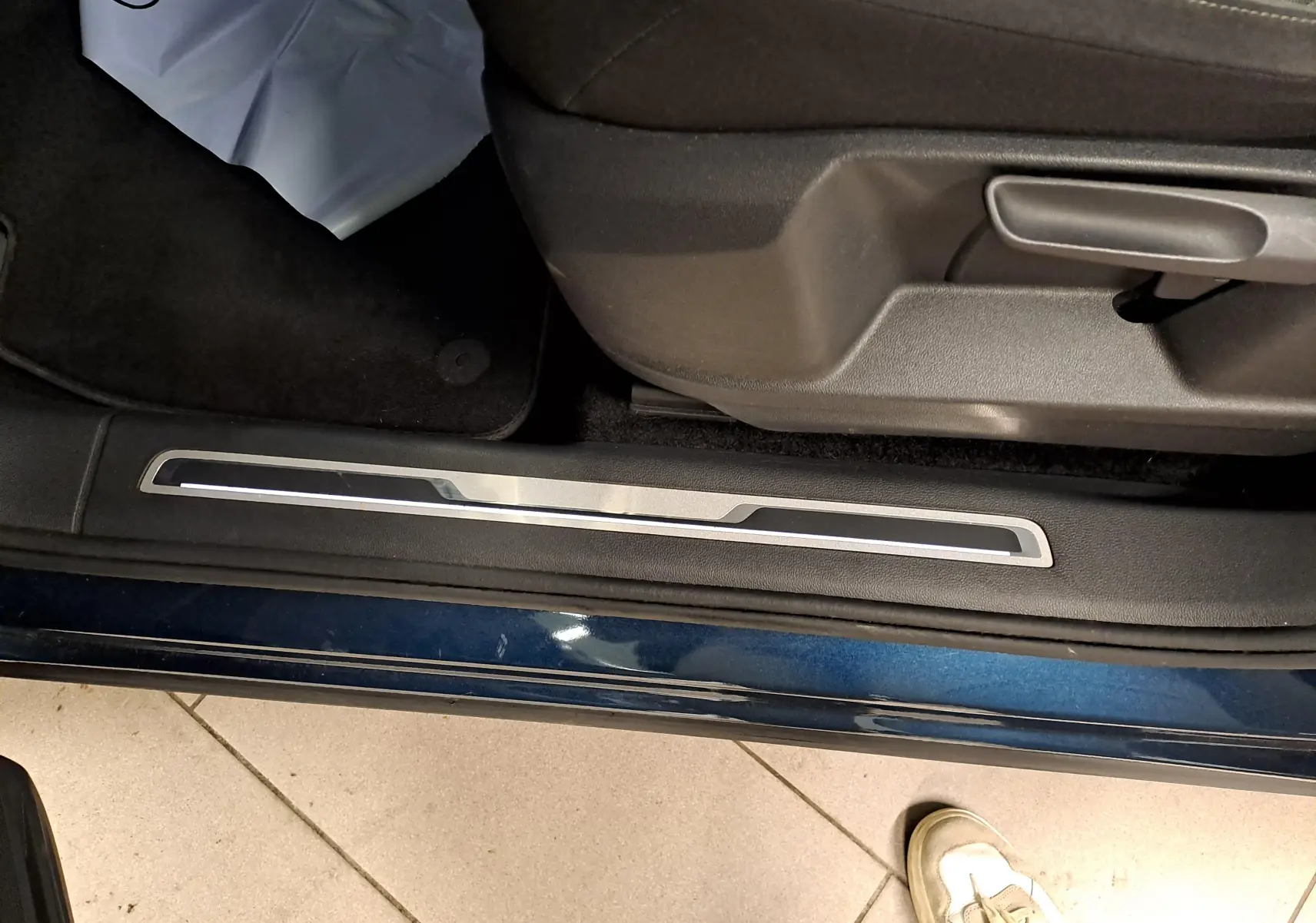 Détail de la partie basse côté gauche d’un Volkswagen Tiguan 2023 en Nightshade Blue avec seuil de porte et siège conducteur.