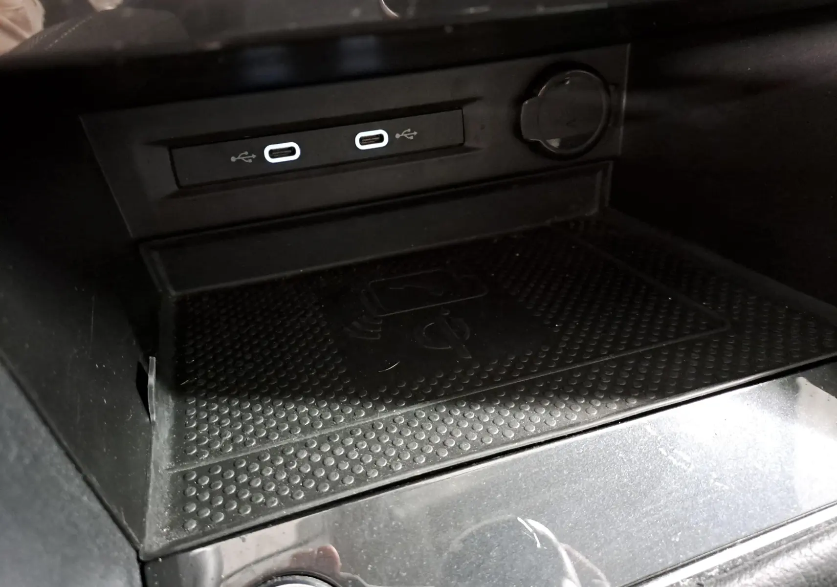 Gros plan sur la console centrale du Volkswagen Tiguan 2023 avec ports USB-C et surface de charge sans fil noire.