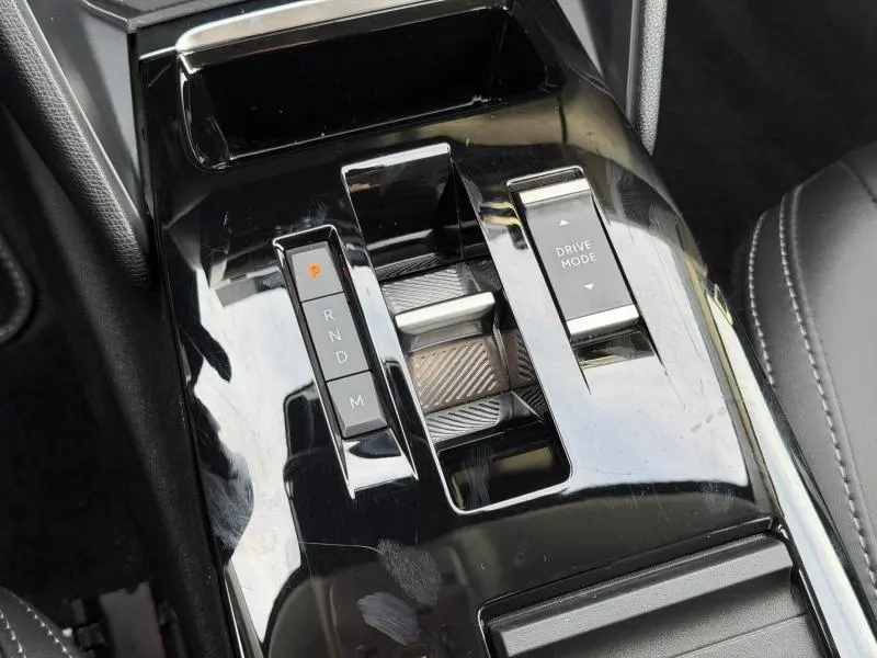 Gros plan sur la console centrale noire brillante du Citroën C4 X 2025 avec commandes de boîte auto et mode de conduite.