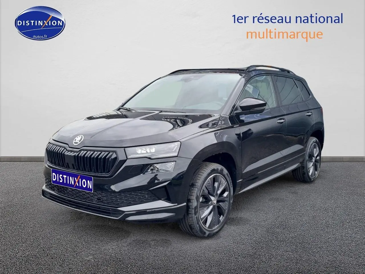 Vue 3/4 avant droite d'un Skoda Karoq noir 2025 avec jantes alu et barres de toit visibles.