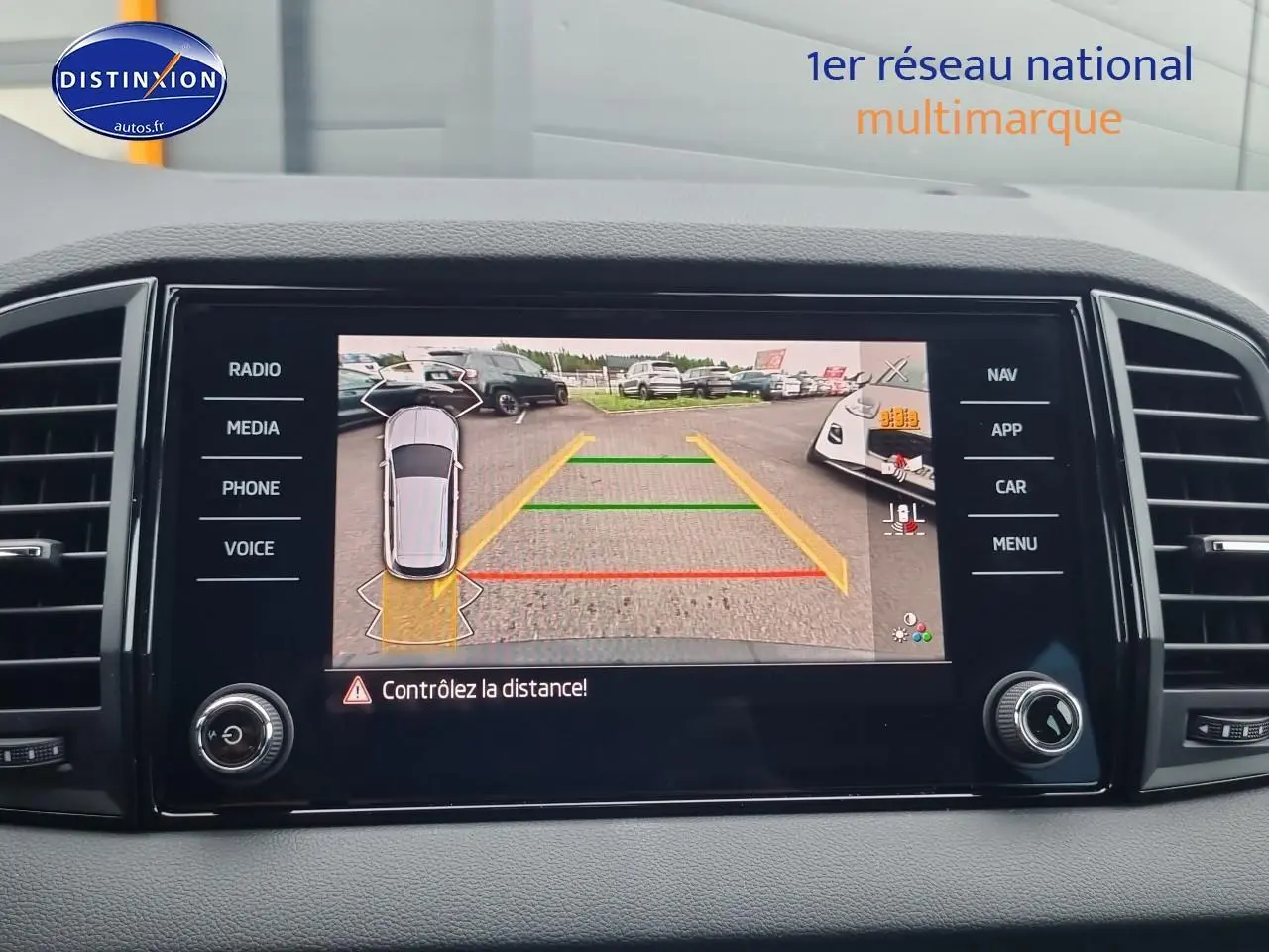 Écran tactile intérieur montrant la caméra de recul avec lignes de guidage du Skoda Karoq noir, vue du tableau de bord.