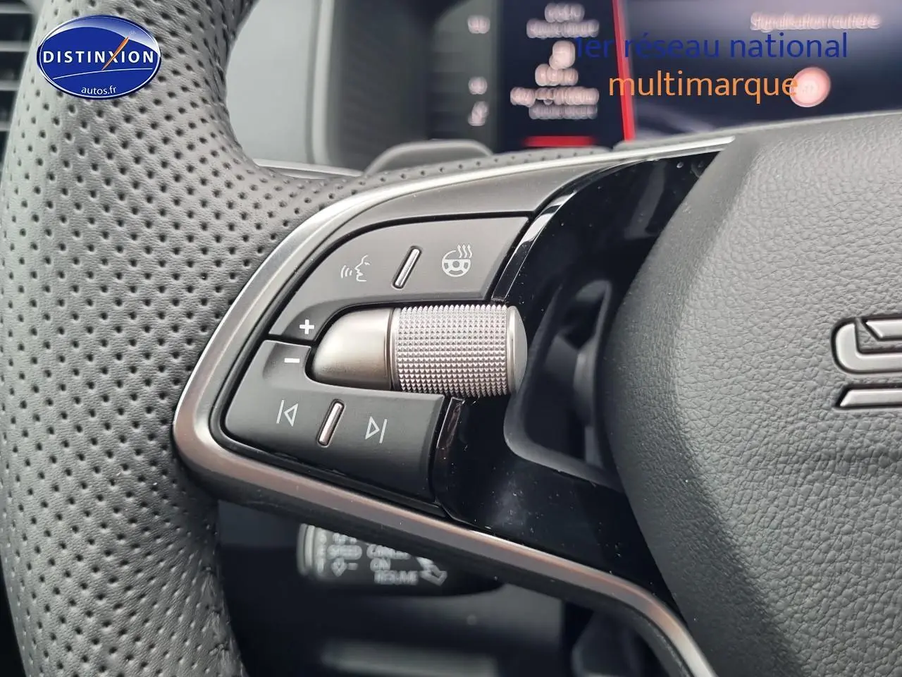 Gros plan sur les commandes gauche du volant cuir perforé du Skoda Karoq noir 2025, avec molette argentée.