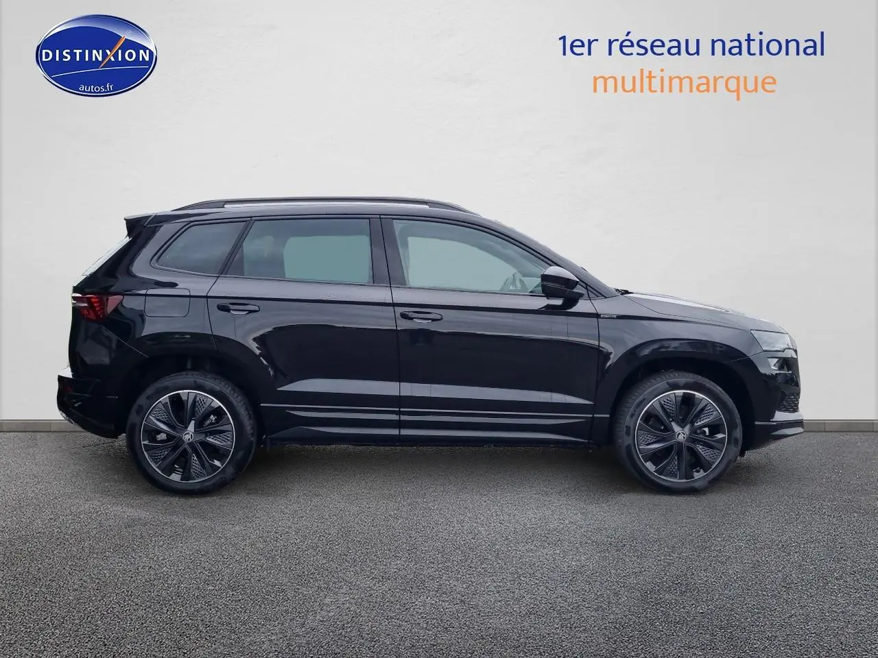 Profil droit d’un Skoda Karoq noir 2025 avec jantes alliage et barres de toit visibles sur fond neutre.