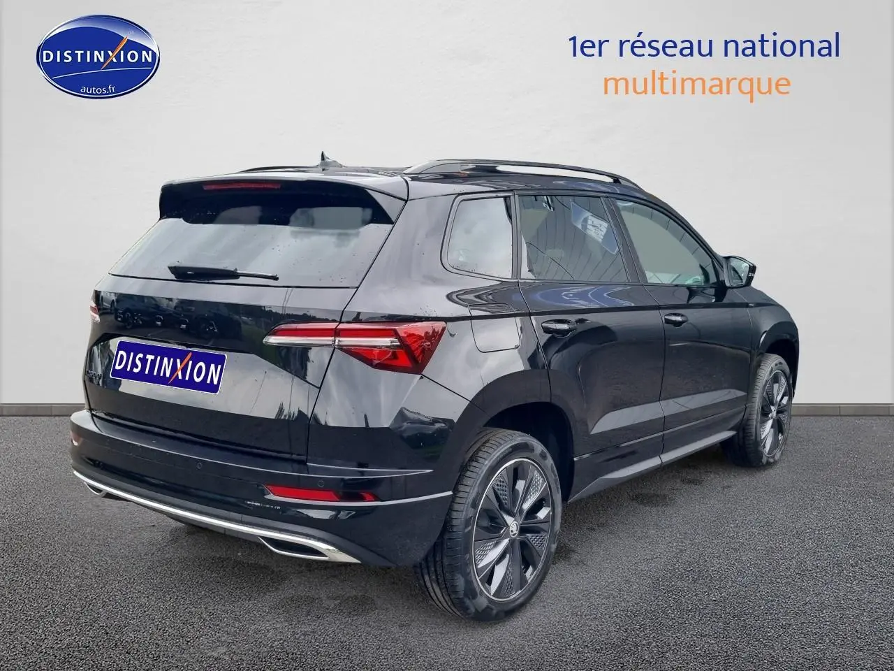 Vue 3/4 arrière droite d'un Skoda Karoq noir 2025 avec jantes alliage et barres de toit visibles.