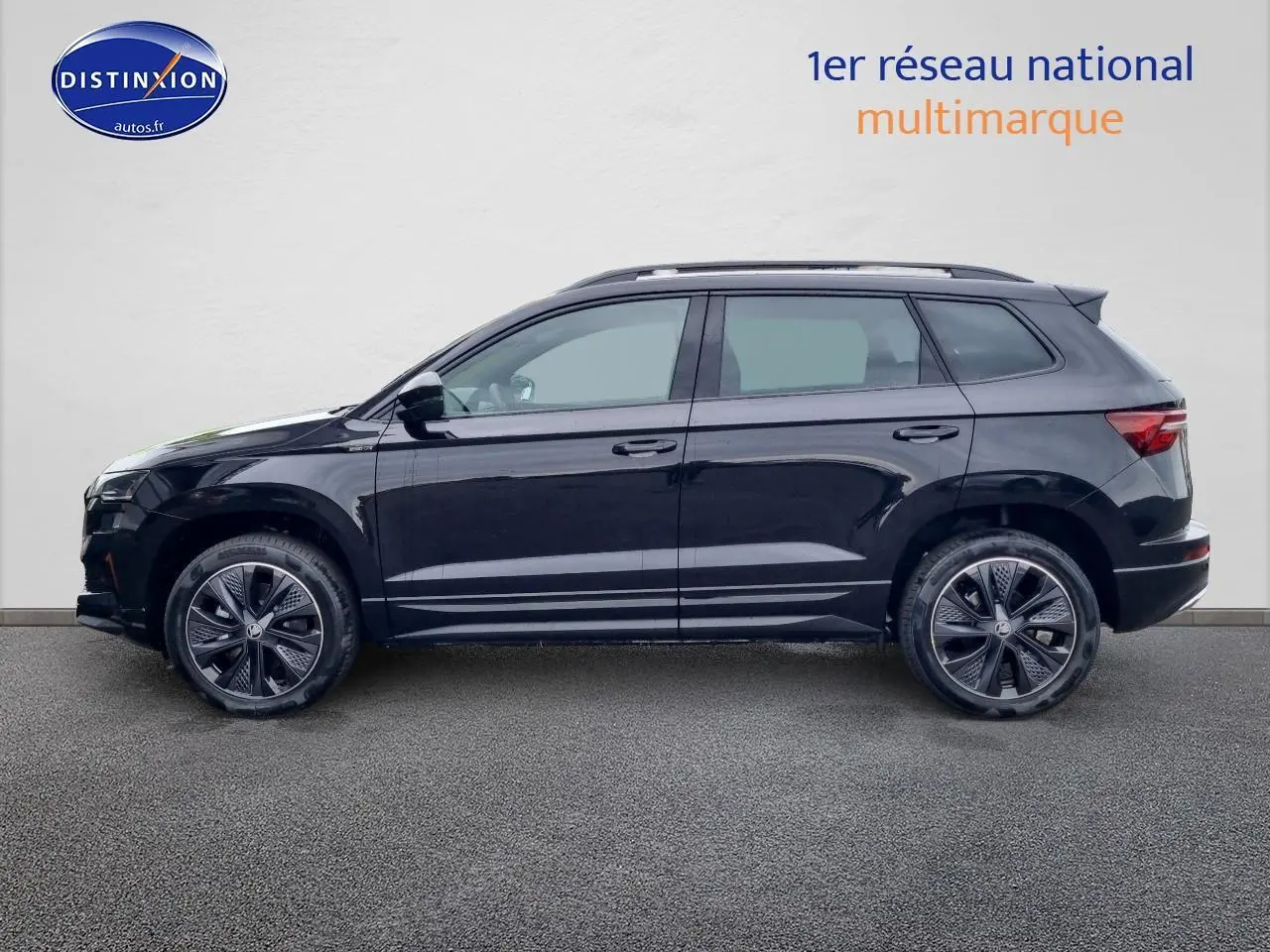 Profil côté gauche d'un Skoda Karoq noir 2025 avec jantes alu et barres de toit visibles.