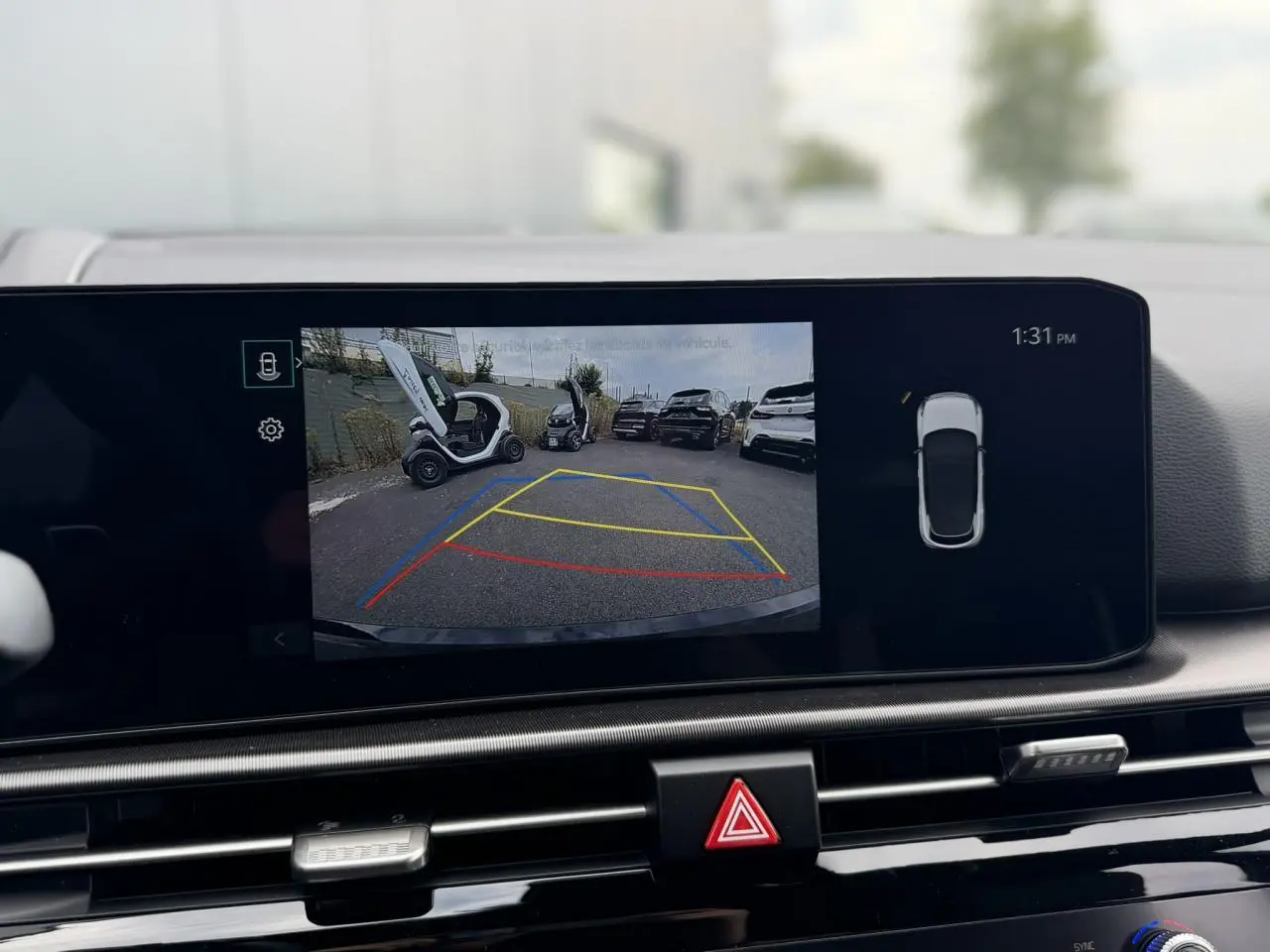 Écran tactile intérieur montrant la caméra de recul du Kia Sportage gris lunaire en stationnement.