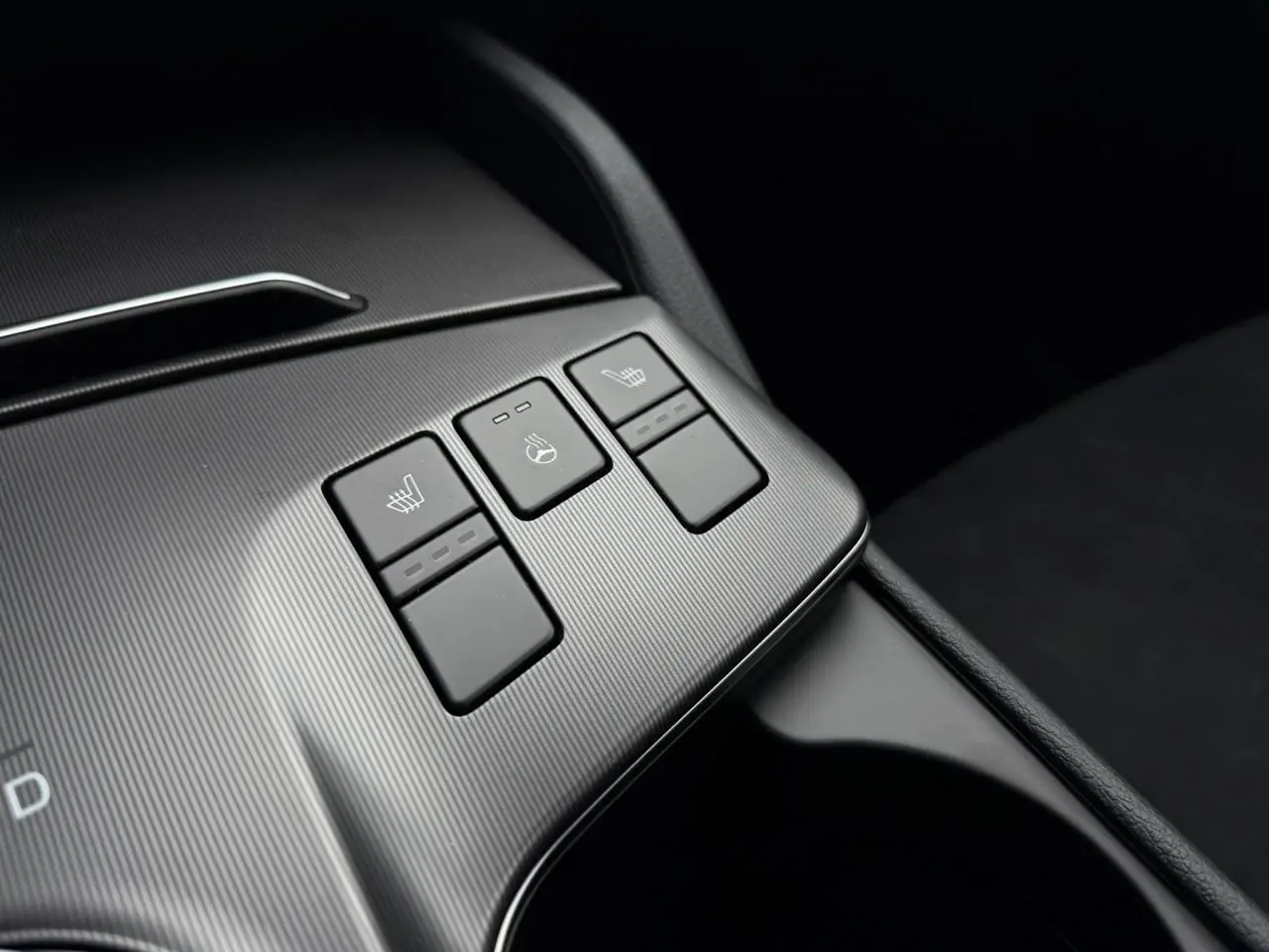 Gros plan sur les commandes de sièges chauffants et volant chauffant du KIA SPORTAGE gris Lunaire, intérieur noir.