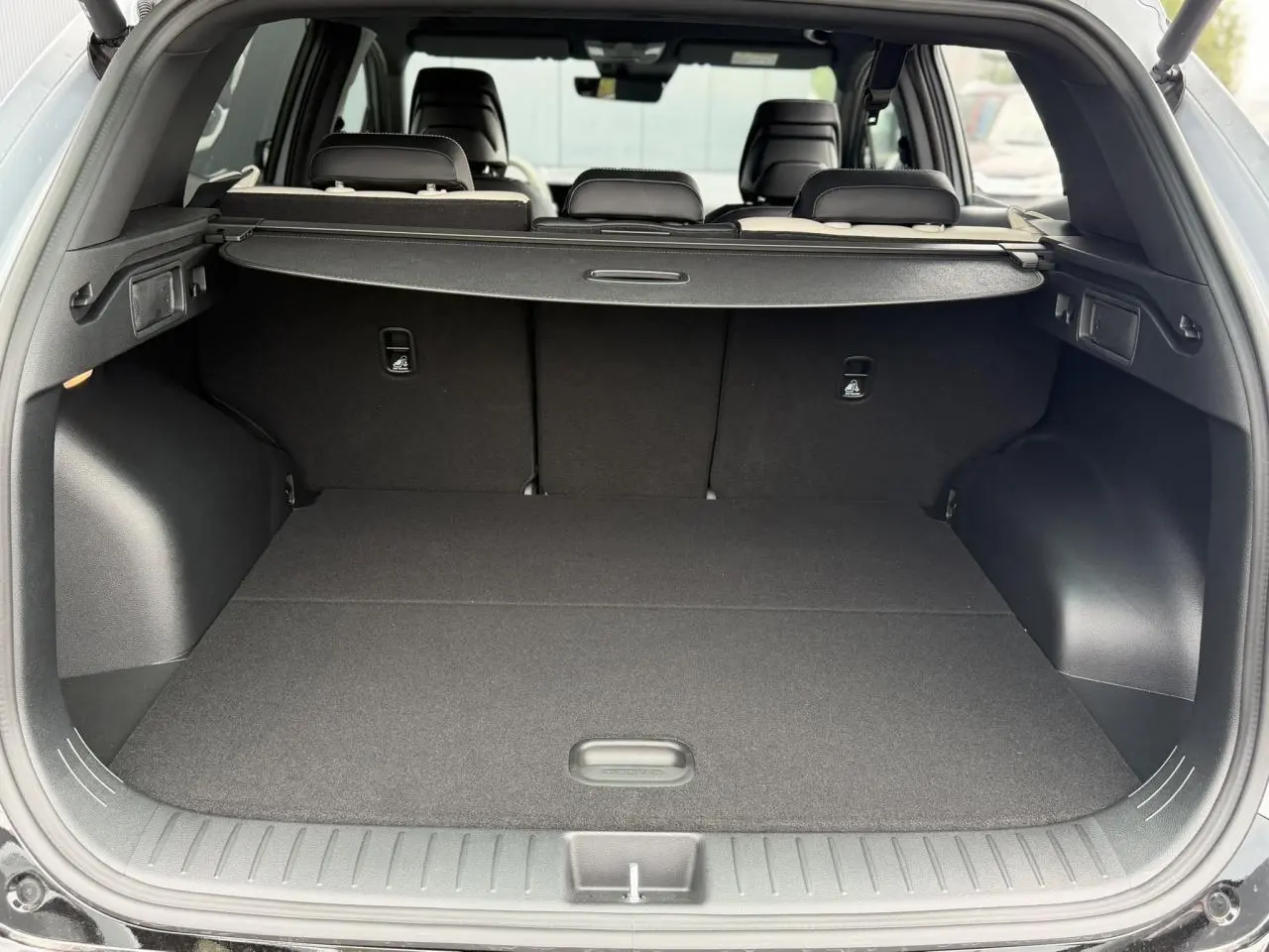 Coffre ouvert vu de l'arrière du KIA SPORTAGE gris lunaire, montrant un espace de chargement plat et couvert.