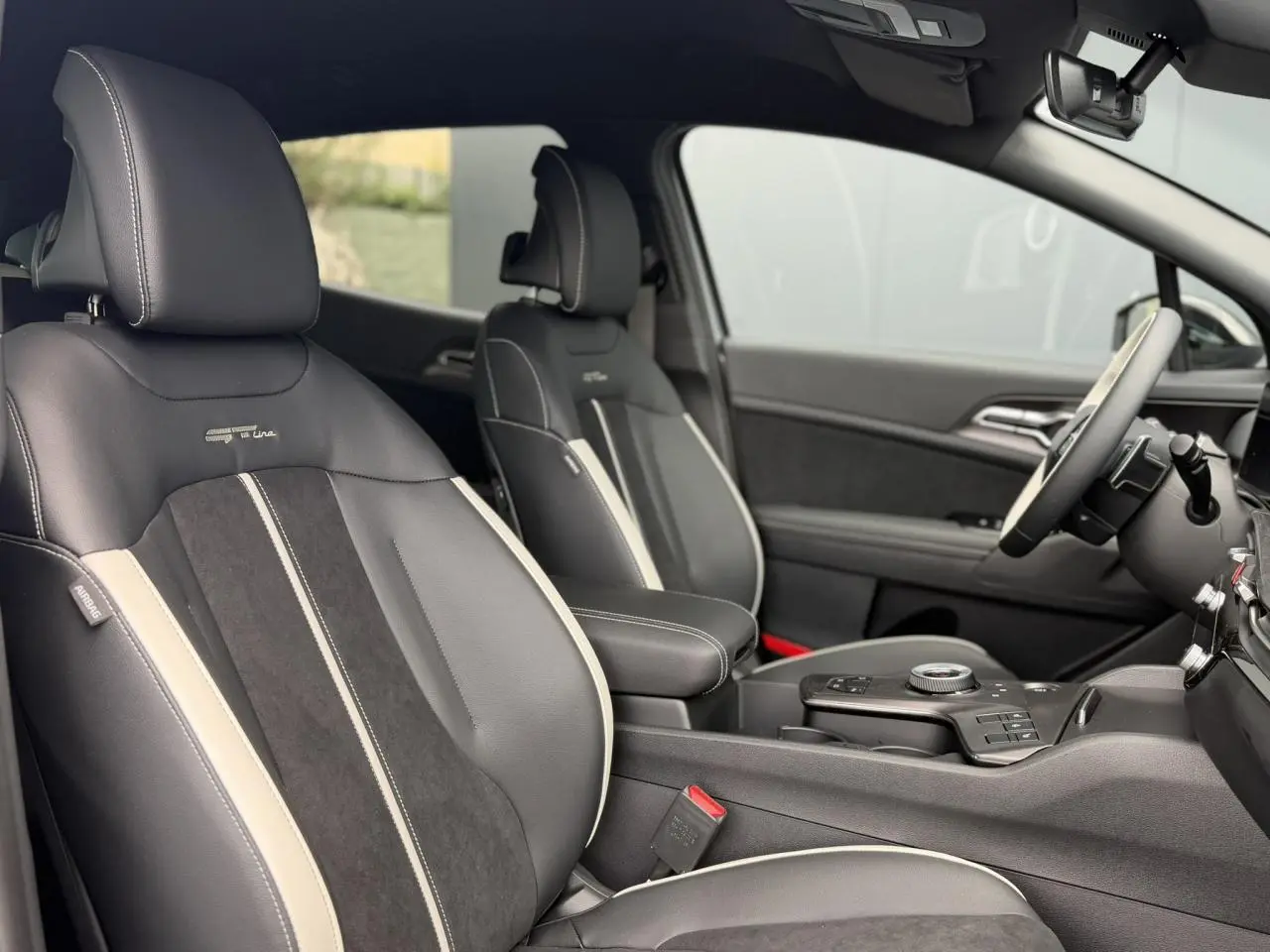 Vue intérieure côté droit du Kia Sportage 2026 GT-line avec sellerie bi-ton noir et gris et volant cuir.