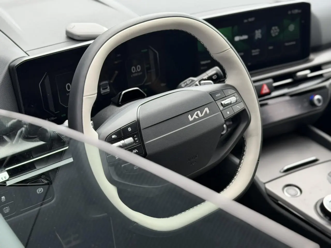 Vue rapprochée du volant bi-ton noir et gris du KIA SPORTAGE 2026 avec tableau de bord digital et écran tactile.