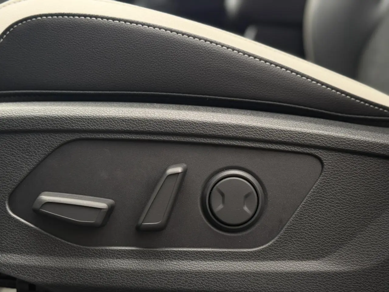 Détail des commandes électriques de réglage lombaire sur le siège avant du KIA SPORTAGE gris Lunaire.
