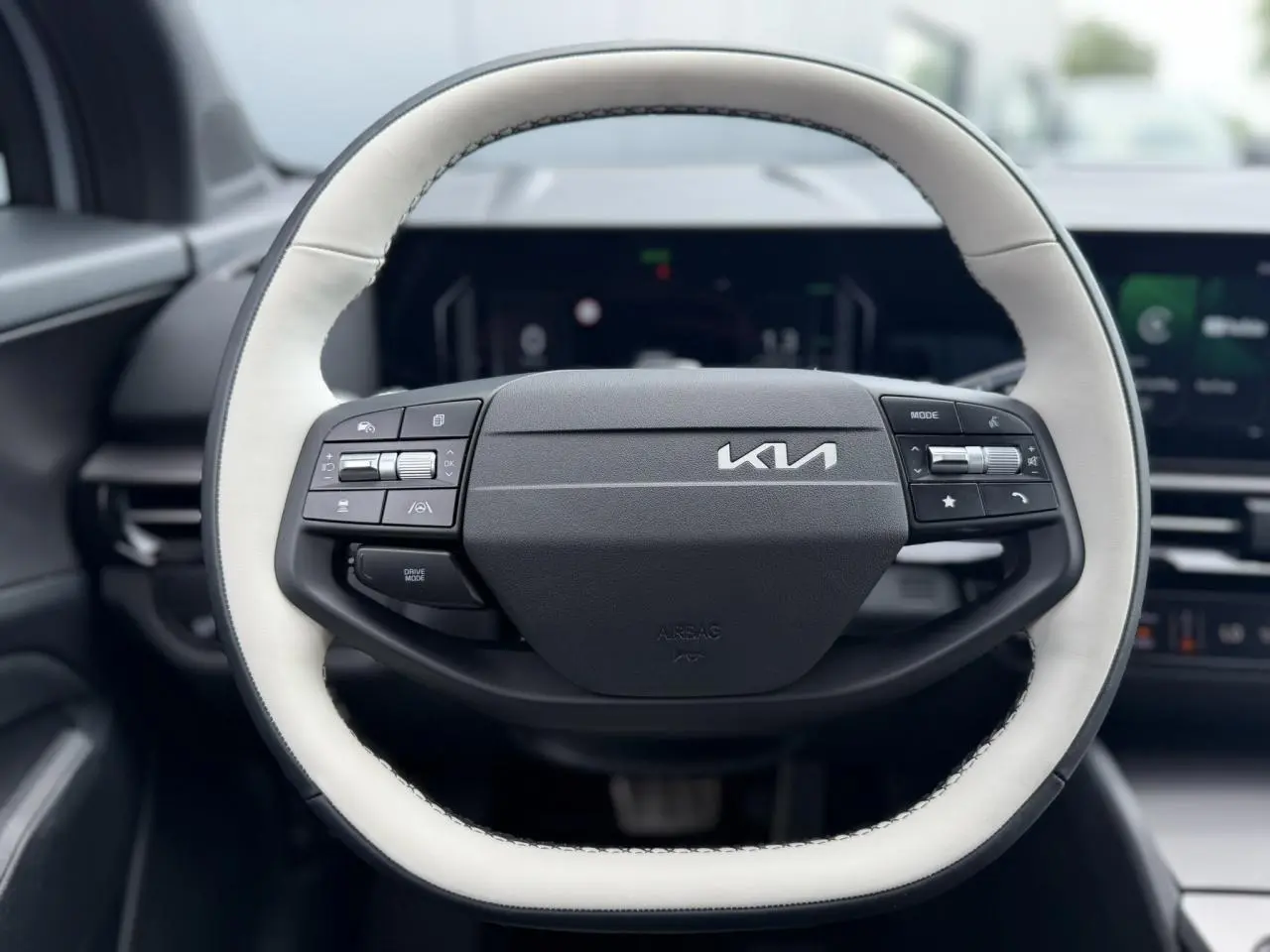 Volant bi-ton noir et blanc du Kia Sportage 2026, vue frontale centrée sur les commandes intégrées.