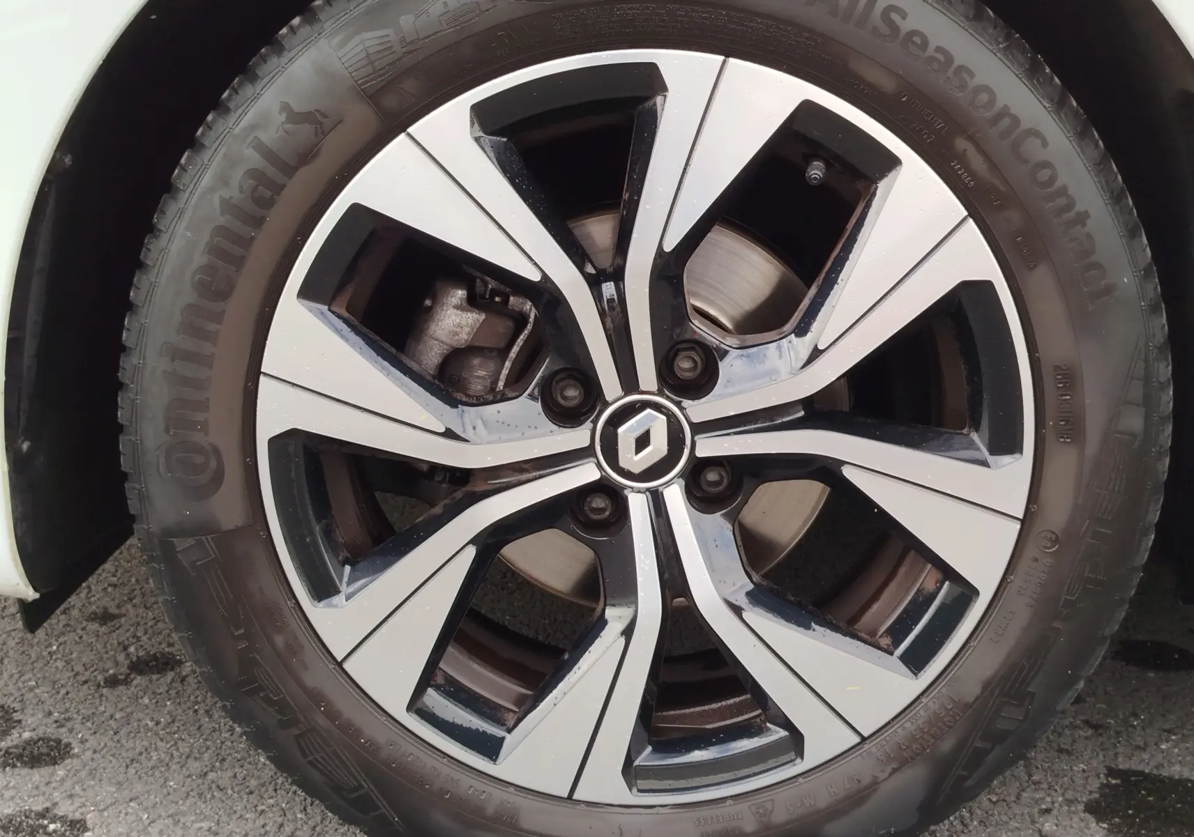 Gros plan sur la jante alliage bicolore noir et argent avec logo Renault, montée sur pneu Continental AllSeason.