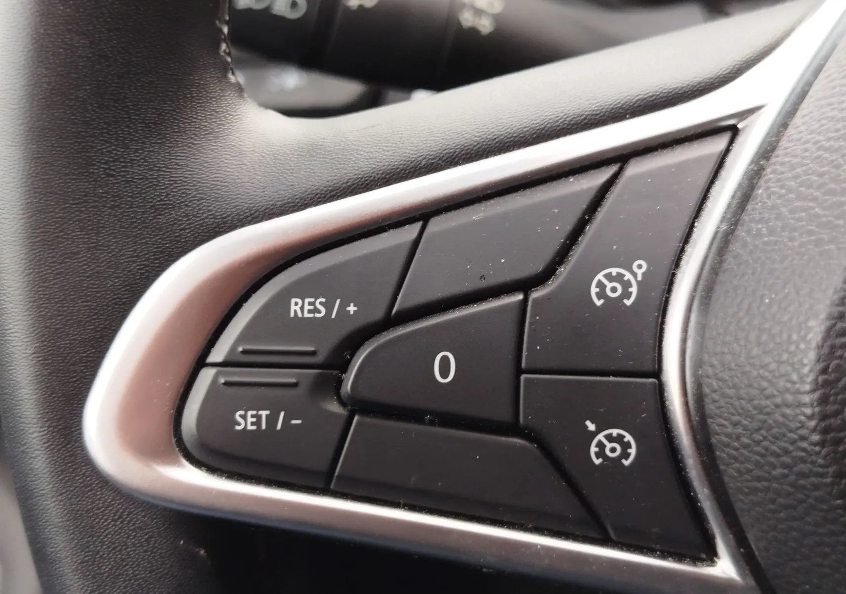Gros plan sur les commandes de régulateur de vitesse au volant noir de la Renault Clio 2023.