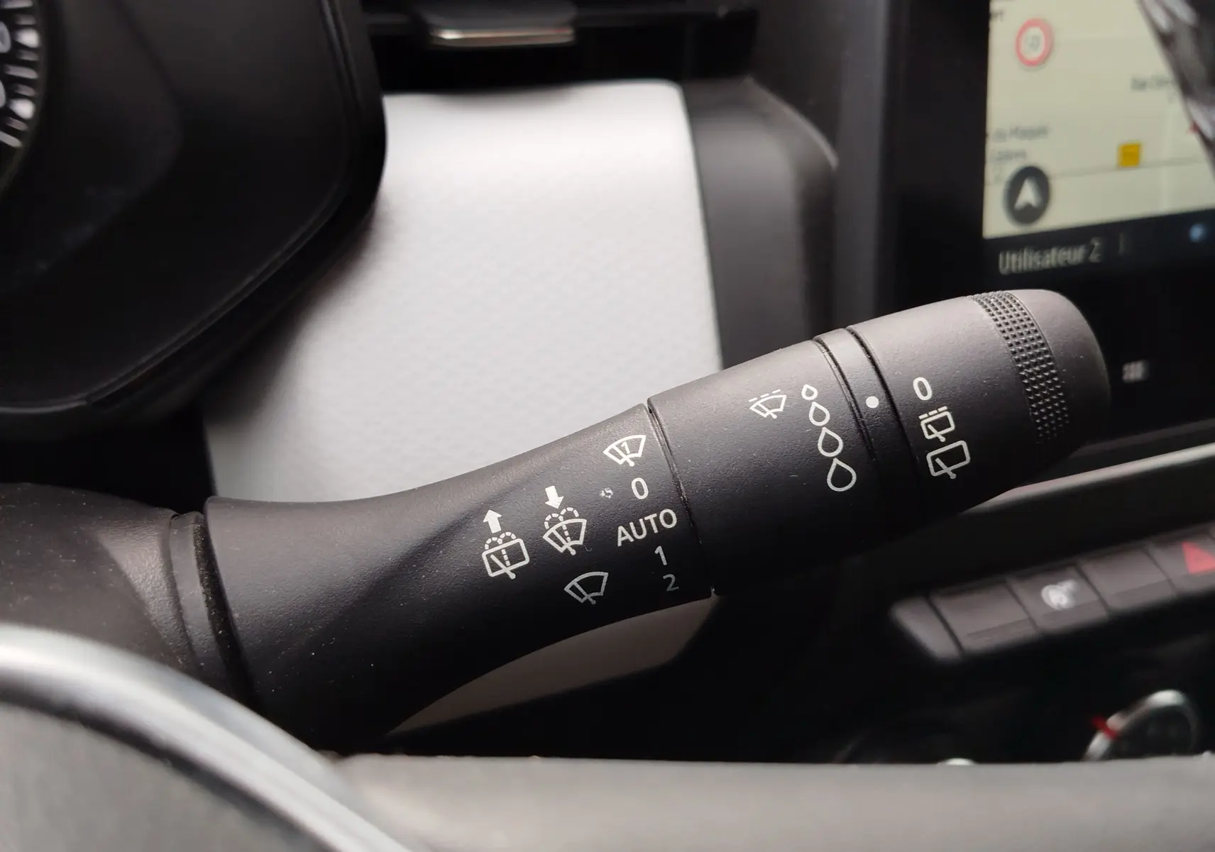 Gros plan sur la commande des essuie-glaces dans l’habitacle blanc et noir d’une Renault Clio 2023.