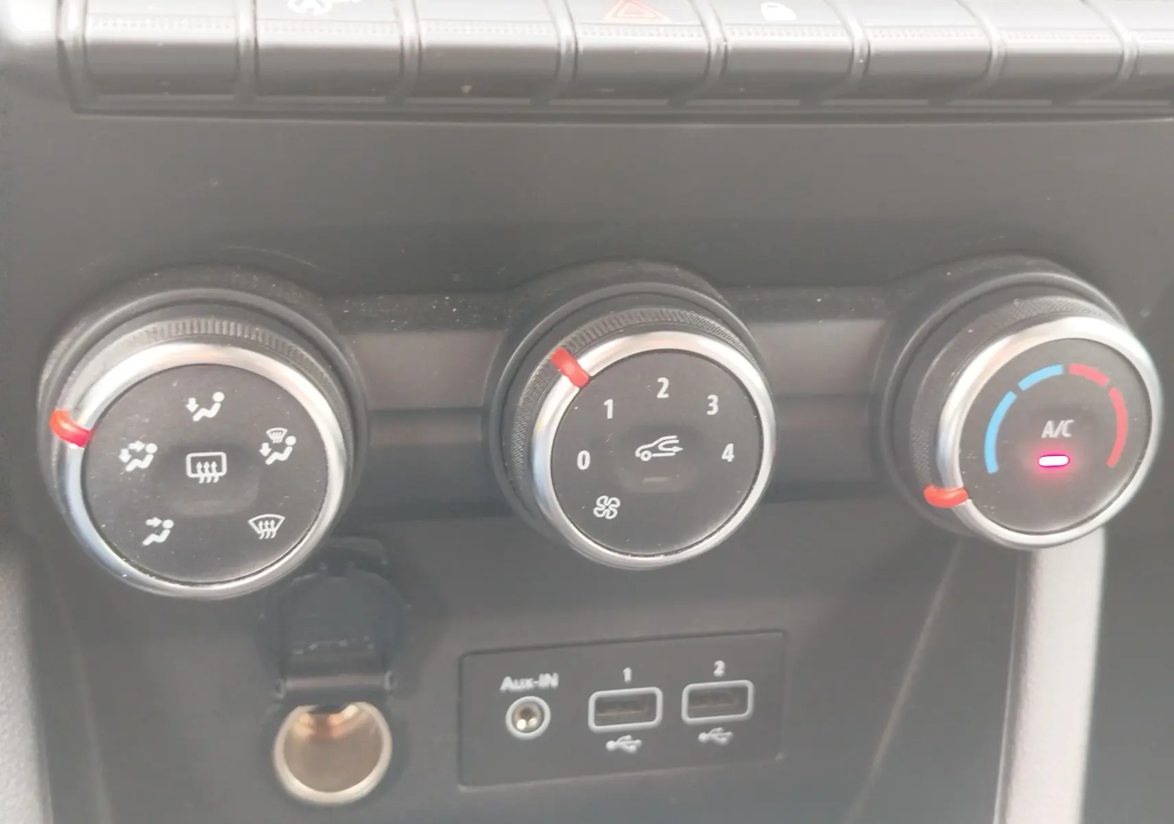 Gros plan sur les commandes de climatisation de la Renault Clio blanche, avec réglages manuels et port USB visibles.