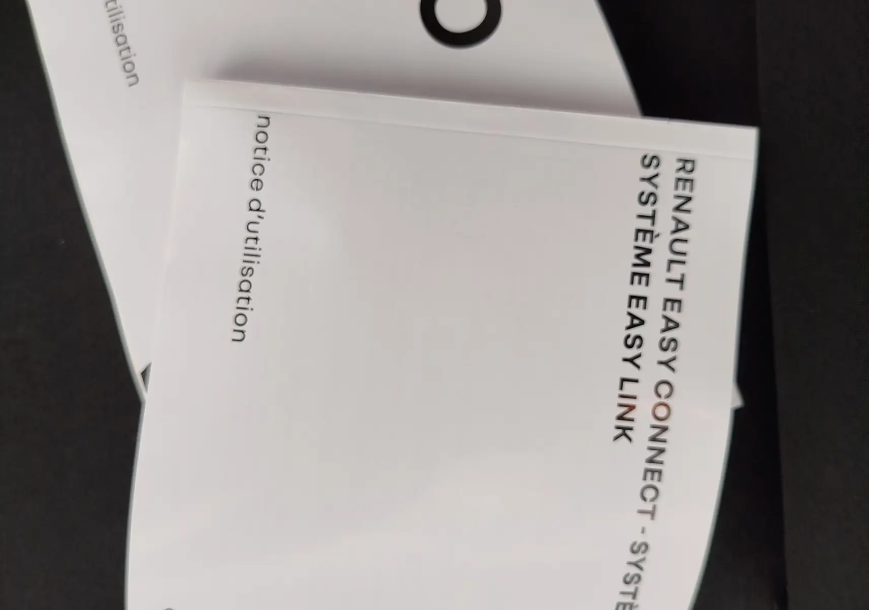 Image ne montrant pas de véhicule, mais deux notices d'utilisation blanches pour Renault Clio et système Easy Link.