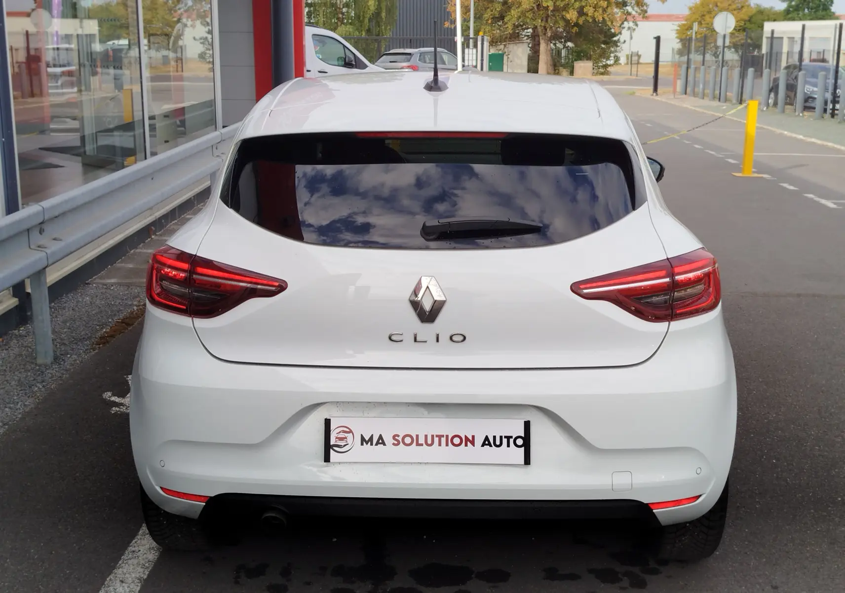 Vue arrière d'une Renault Clio blanche Glacier 2023, avec feux LED allumés et vitre arrière teintée.