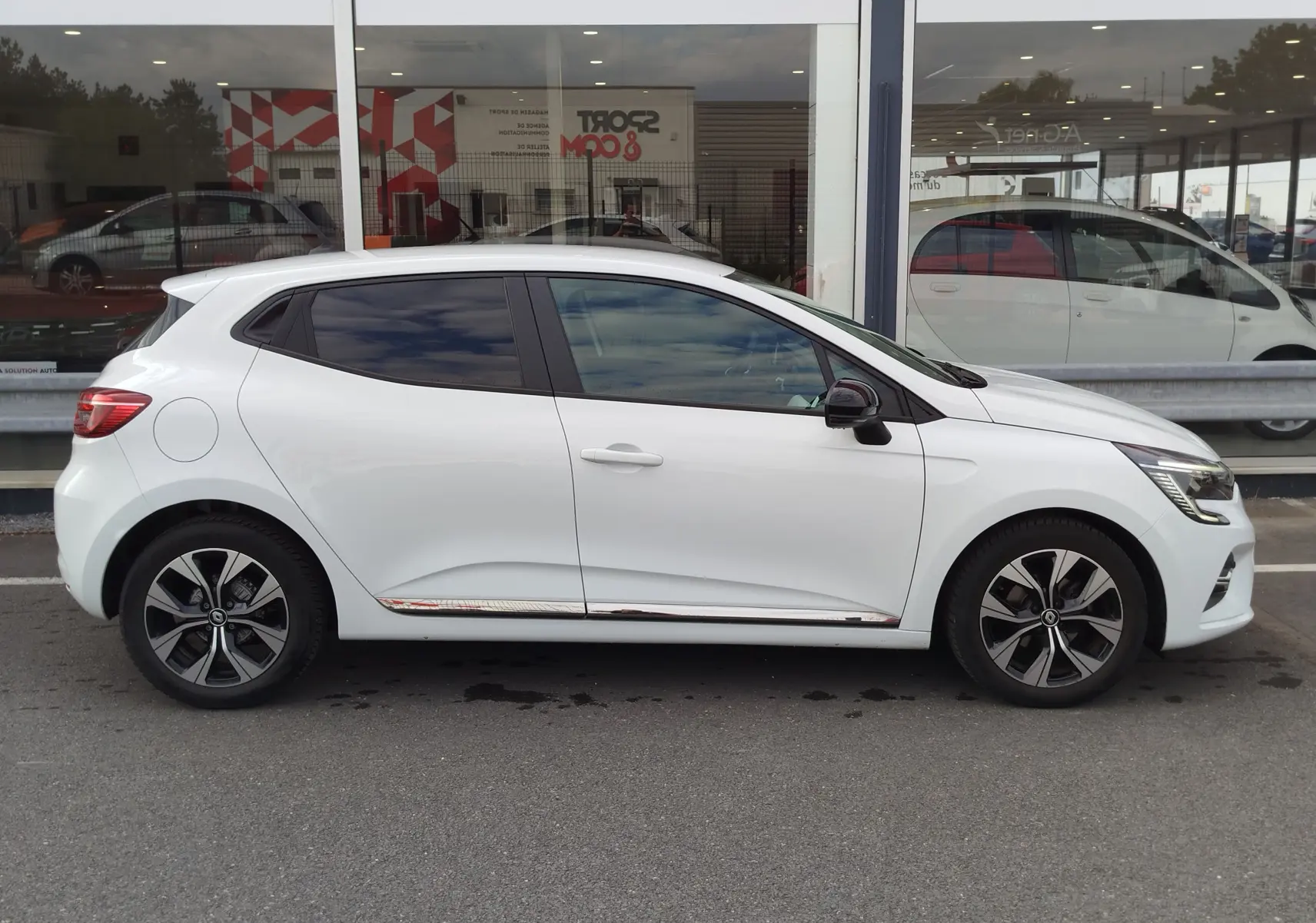 Profil droit d'une Renault Clio 1.0 SCe 65ch Evolution blanche Glacier avec jantes alliage et vitres teintées.