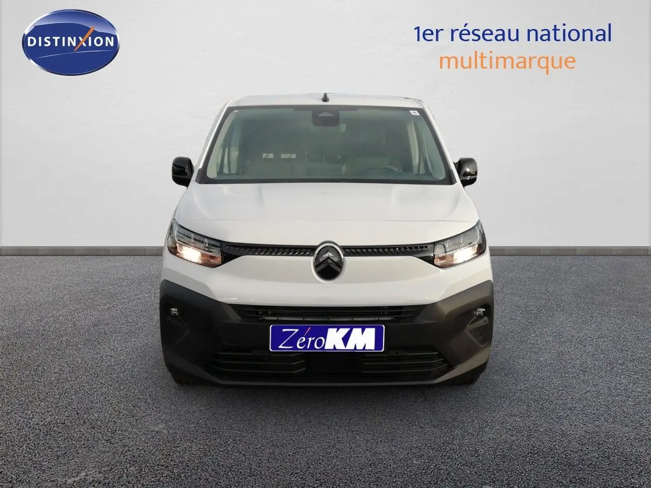 Vue de face du Citroën Berlingo XL blanc Icy avec calandre noire et phares allumés sur fond neutre.