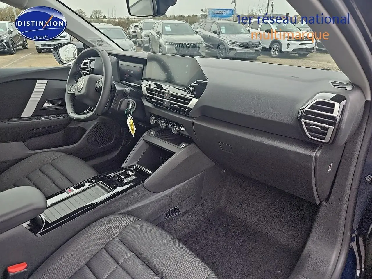 Intérieur avant droit de la Citroën C4 1.2 hybride 136 plus bleu eclipse avec tableau de bord moderne et sièges tissu noir.