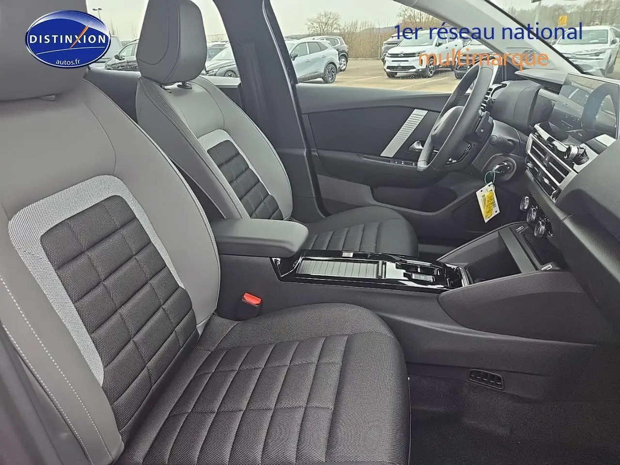 Vue intérieure côté droit de la Citroën C4 1.2 hybride 136 plus, sièges tissu noir et gris avec console centrale brillante.