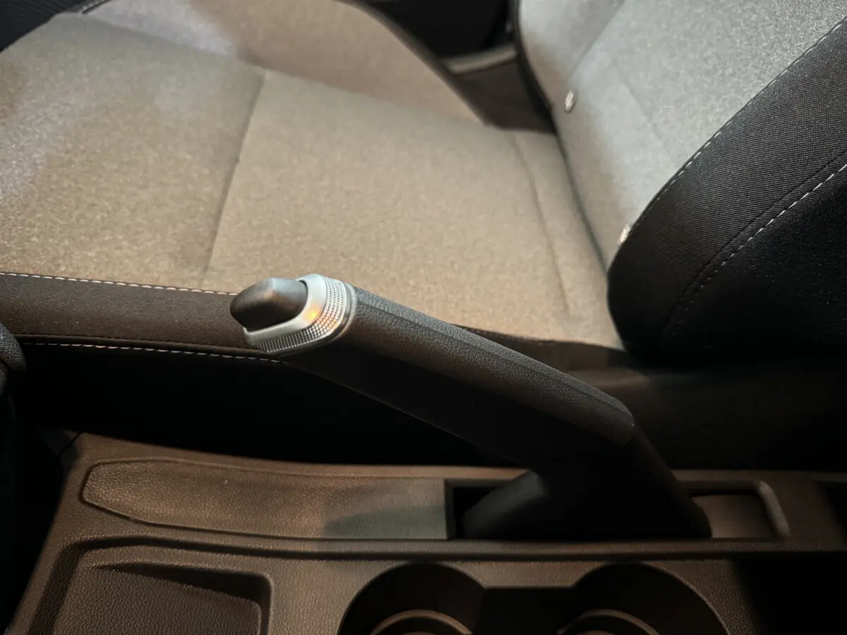 Le levier de frein à main noir et gris dans l'habitacle de la Renault Clio Evolution Blue dCi 100, siège tissu gris visible.