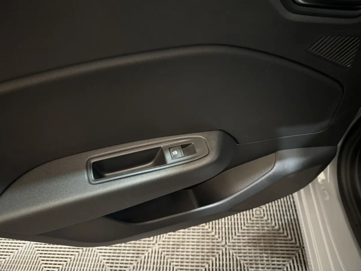 Gros plan sur la poignée intérieure côté gauche d'une Renault Clio gris clair, avec bouton de verrouillage des portes.