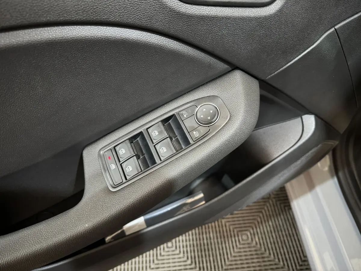 Commande des vitres et rétroviseurs côté conducteur sur porte intérieure grise claire d'une Renault Clio 2025.