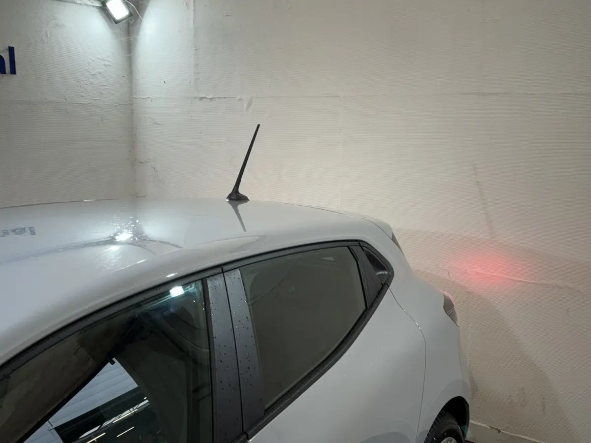 Vue arrière côté gauche d'une Renault Clio gris clair 2025 avec antenne sur le toit et vitre arrière teintée.