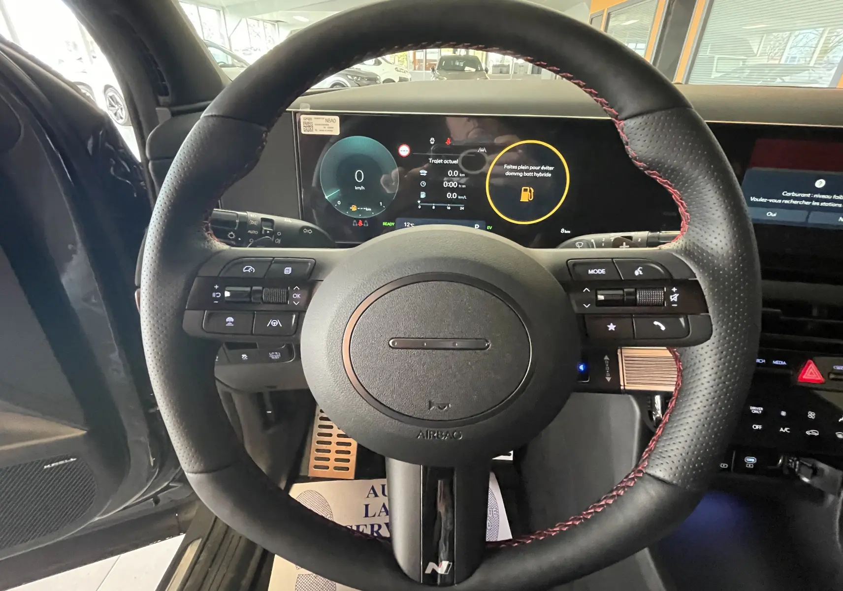 Vue intérieure centrée sur le volant N Line noir avec surpiqûres rouges du Hyundai Tucson gris Ecotronic 2025.