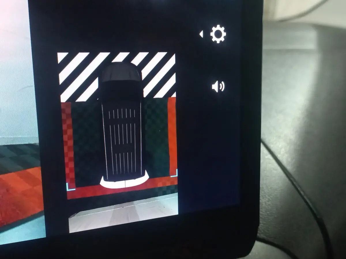 Vue écran caméra de recul montrant le dessus du Citroën Berlingo blanc XL en stationnement avec marquage au sol rouge et blanc.