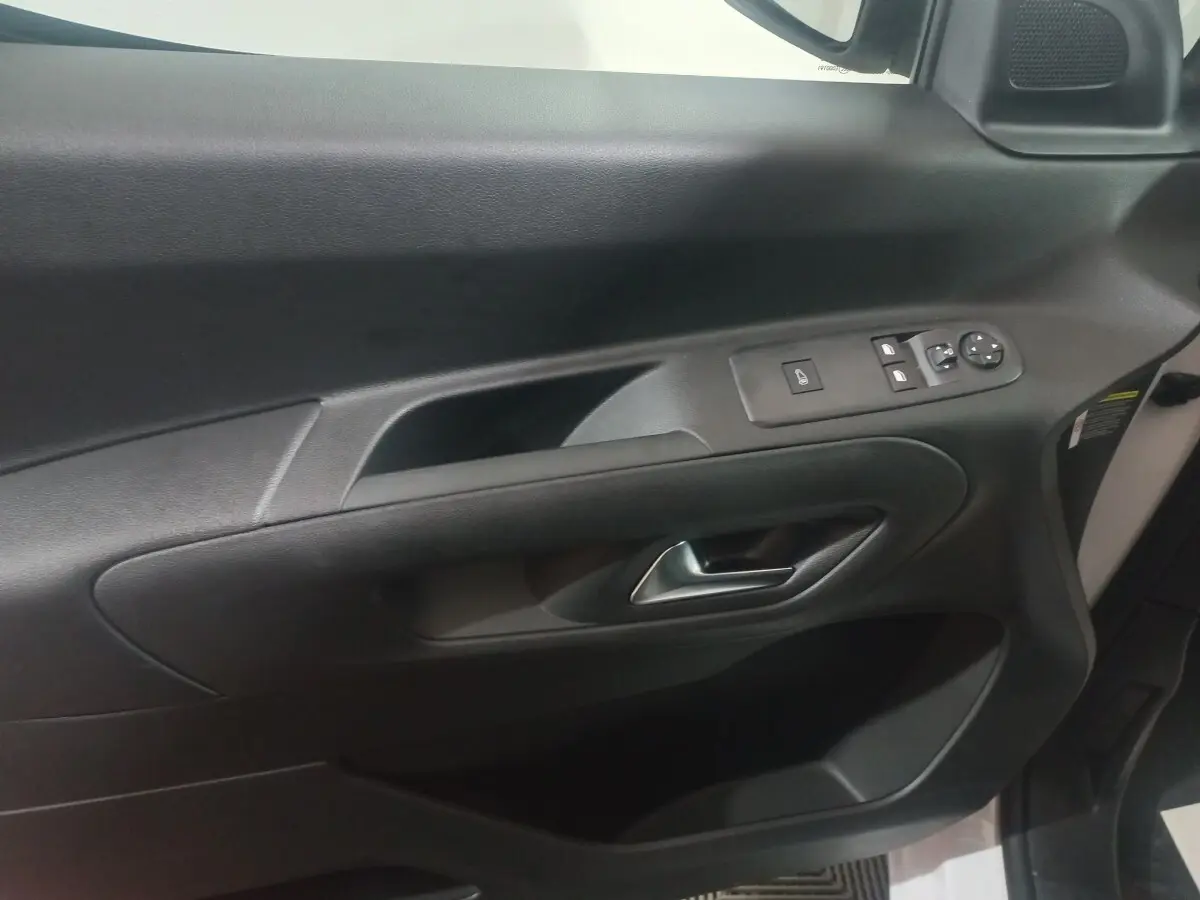 Vue intérieure du panneau de porte côté conducteur du Citroën Berlingo blanc, avec commandes électriques et poignée chrome.