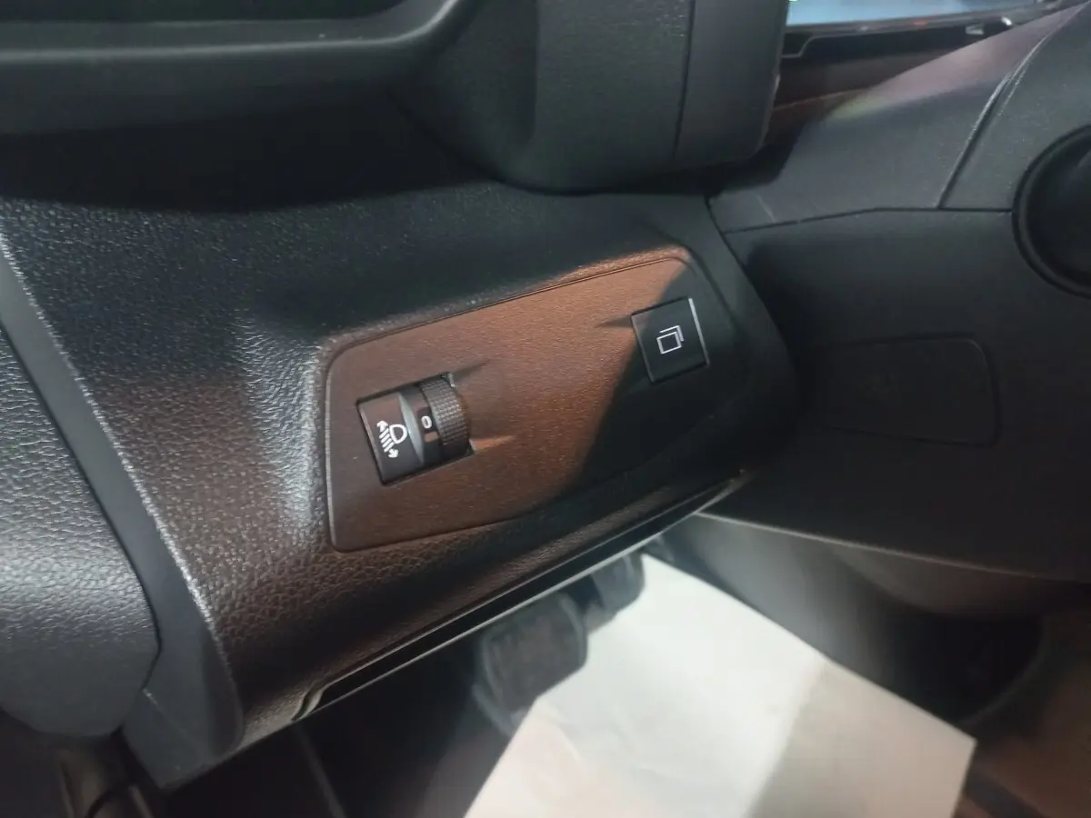 Détail du tableau de bord noir du Citroën Berlingo XL 2025, avec commandes d'éclairage et réglage des rétroviseurs.