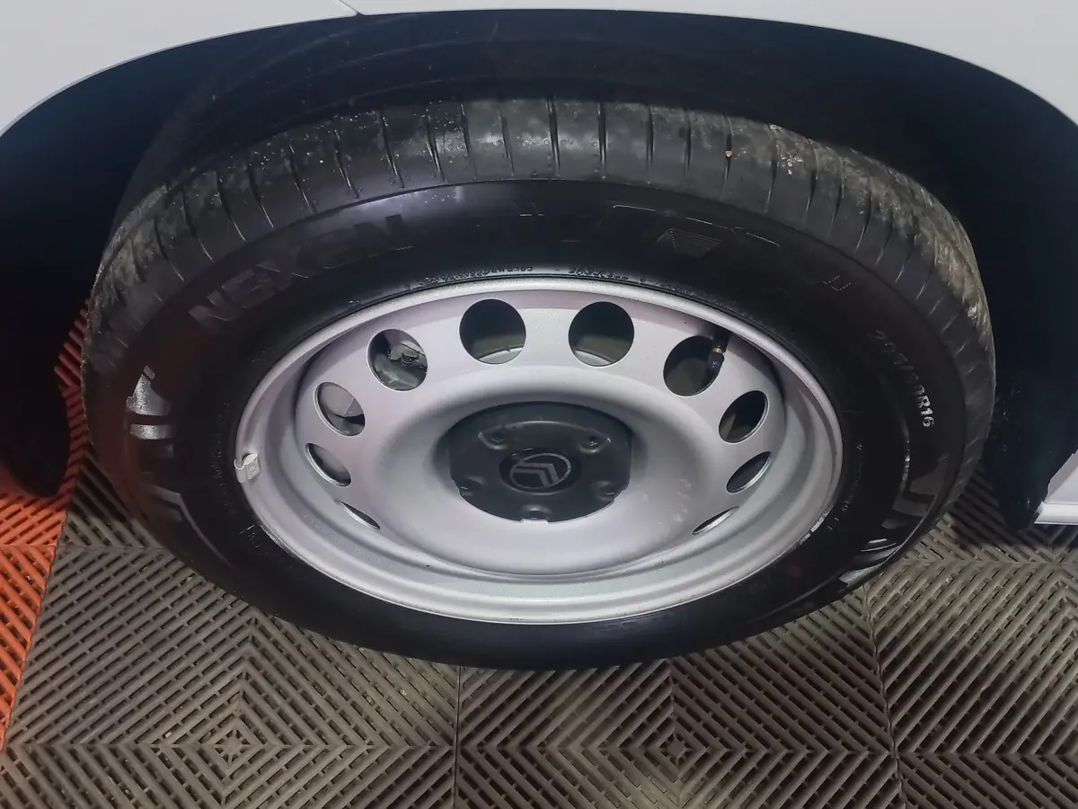 Gros plan sur la roue avant droite avec jante acier grise et logo Citroën sur un véhicule blanc.