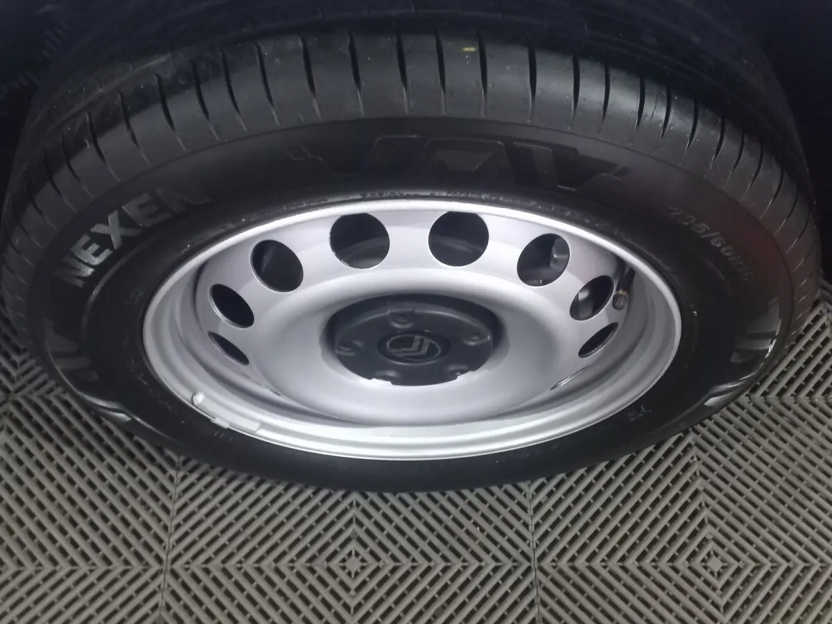 Gros plan sur la roue acier argentée avec pneu Nexen d’un Citroën Berlingo blanc, vue de dessus.