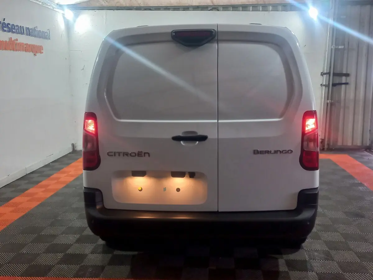 Vue arrière d’un utilitaire blanc Citroën Berlingo XL 2025 avec feux arrière allumés dans un garage.