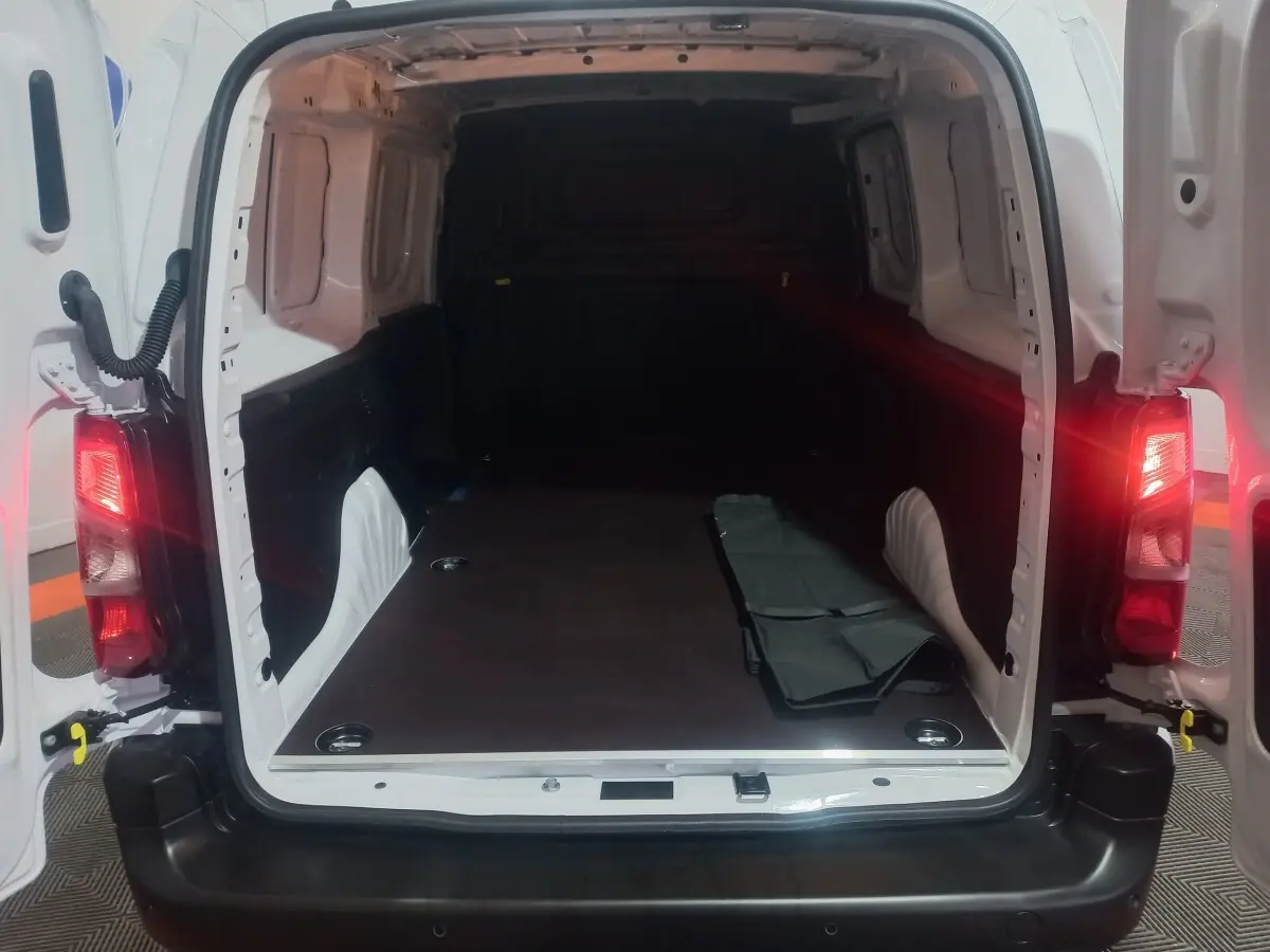 Vue arrière ouverte du Citroën Berlingo XL blanc 2025, montrant l’espace de chargement vide avec plancher plat et tapis partiel.