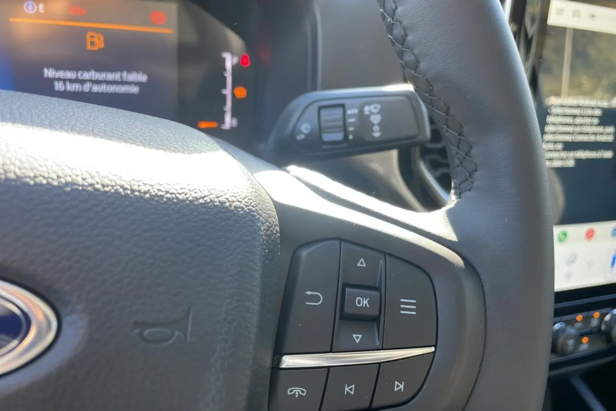 Gros plan sur le volant cuir multifonctions du Ford Ranger gris iconic, tableau de bord et écran tactile en arrière-plan.