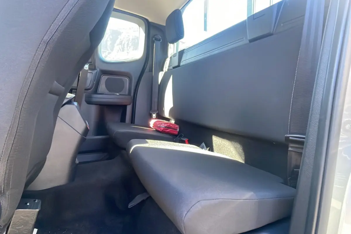 Vue intérieure arrière côté droit du Ford Ranger gris iconic, banquette simple avec trousse de secours rouge posée dessus.