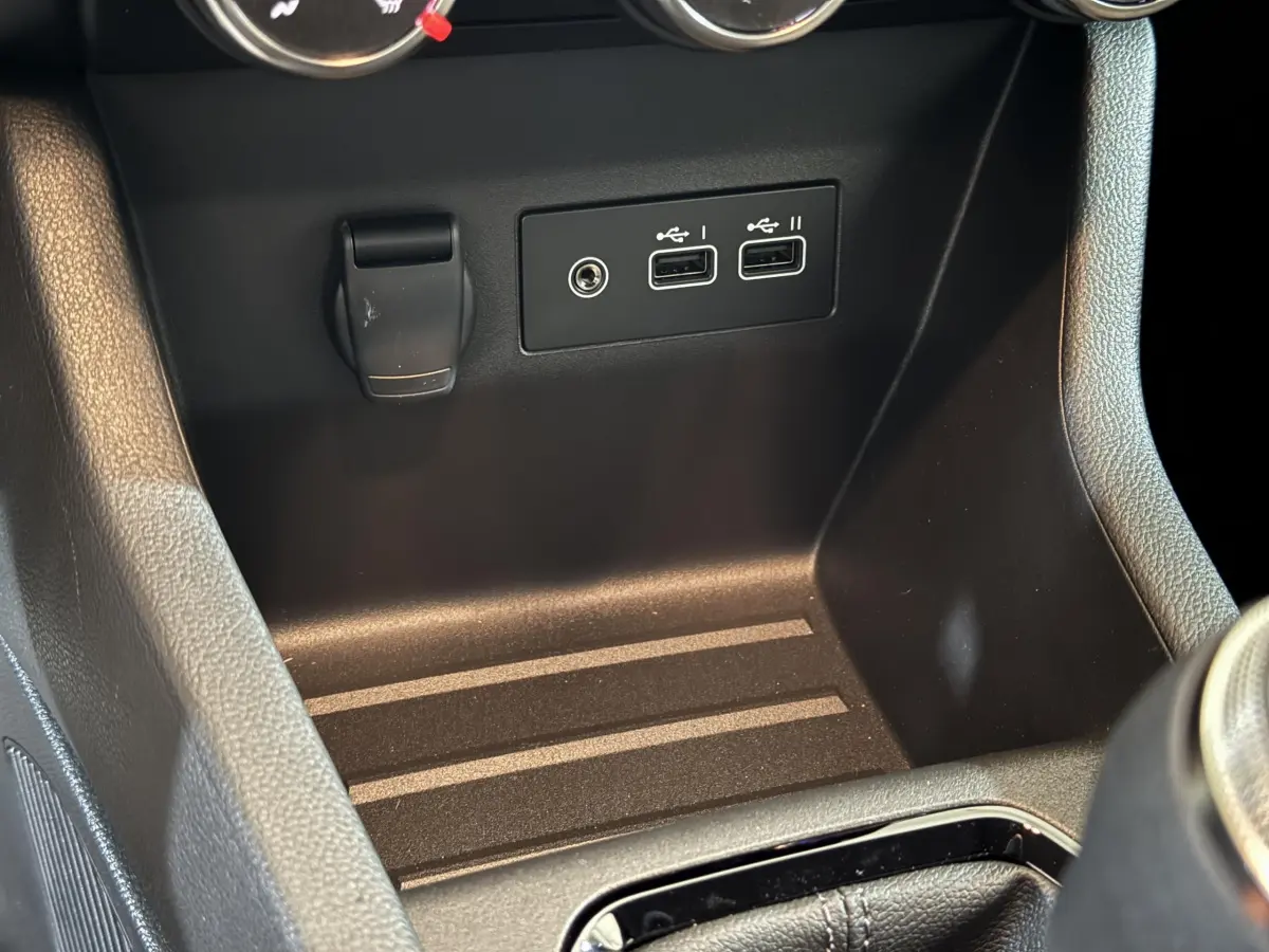 Vue rapprochée de la console centrale noire avec prises USB et prise 12V de la Renault Clio gris clair 2025.