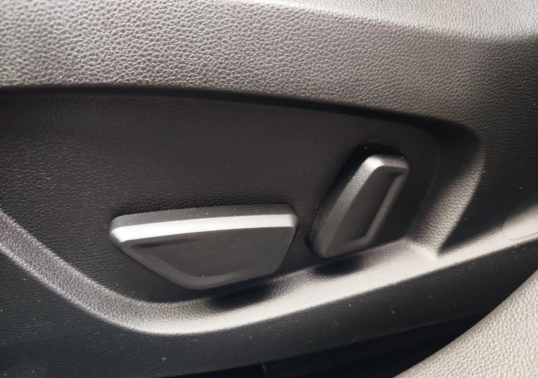 Gros plan sur les commandes de réglage électrique du siège en plastique noir dans l'habitacle du Renault Symbioz 2025.