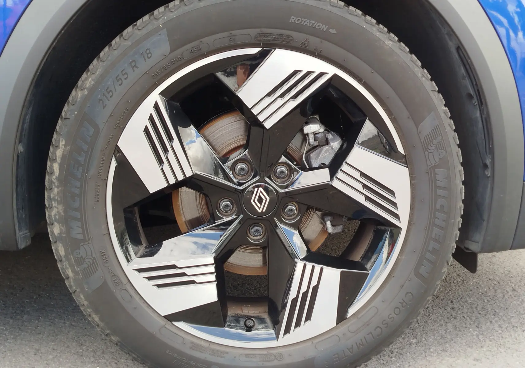 Gros plan sur la roue avant droite du Renault Symbioz 2025 bleu iron metal avec jante alliage bicolore et logo Renault central.