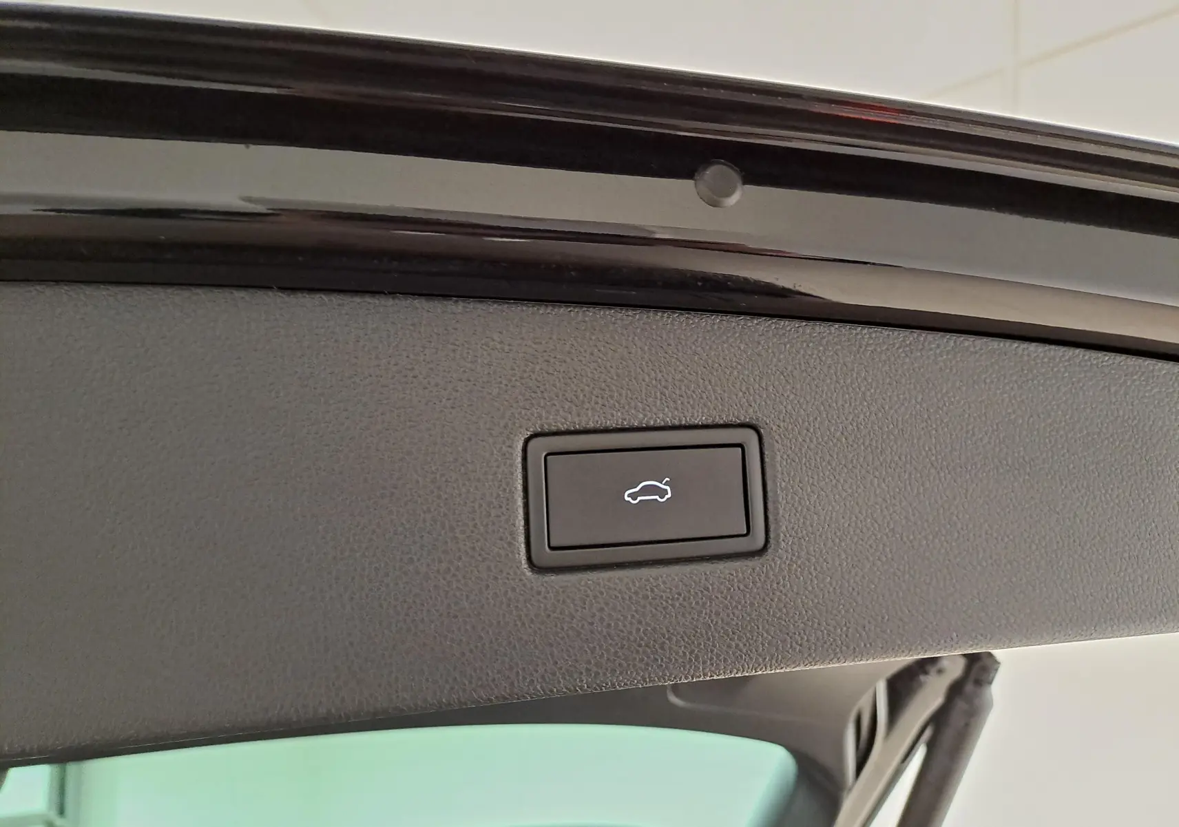Bouton d'ouverture électrique du hayon sur la partie intérieure du coffre d'un Volkswagen Tiguan noir intense nacré.