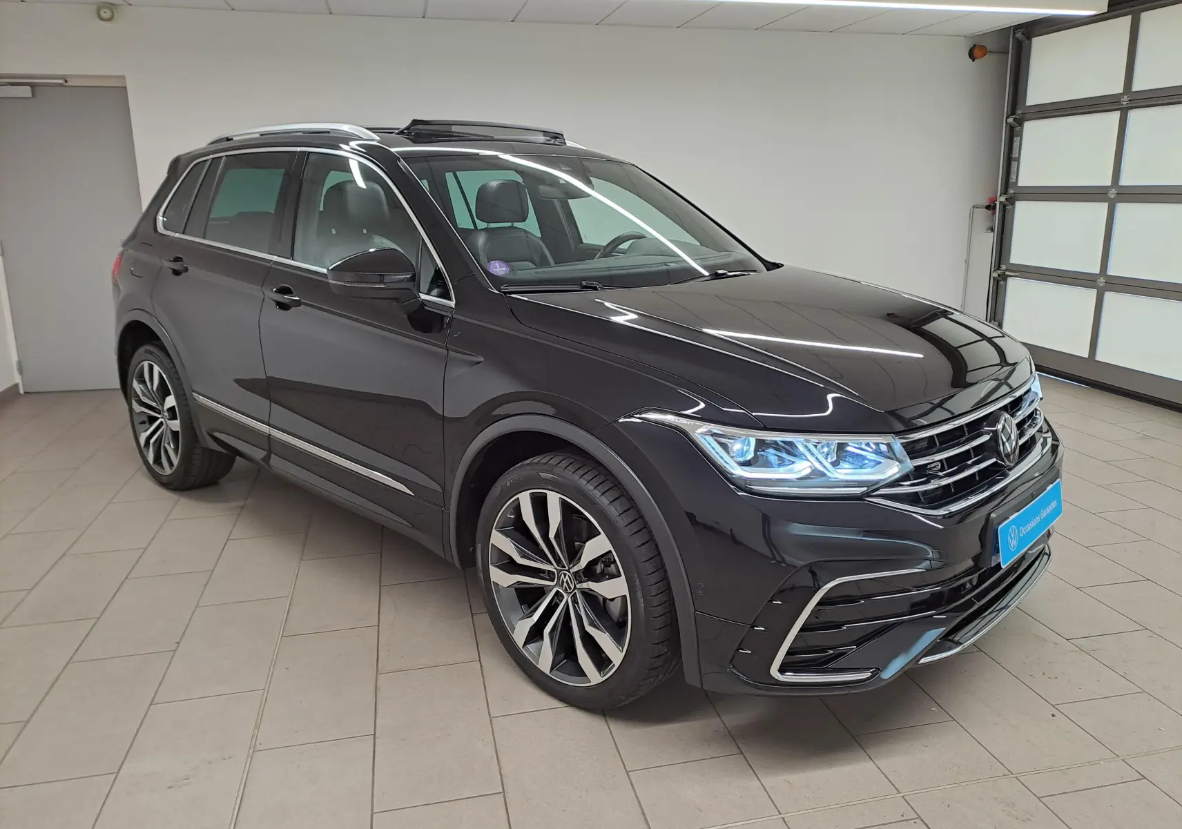 Volkswagen Tiguan 1.4 eHybrid noir nacré en 3/4 avant droit avec jantes 20'' Suzuka et feux LED allumés.