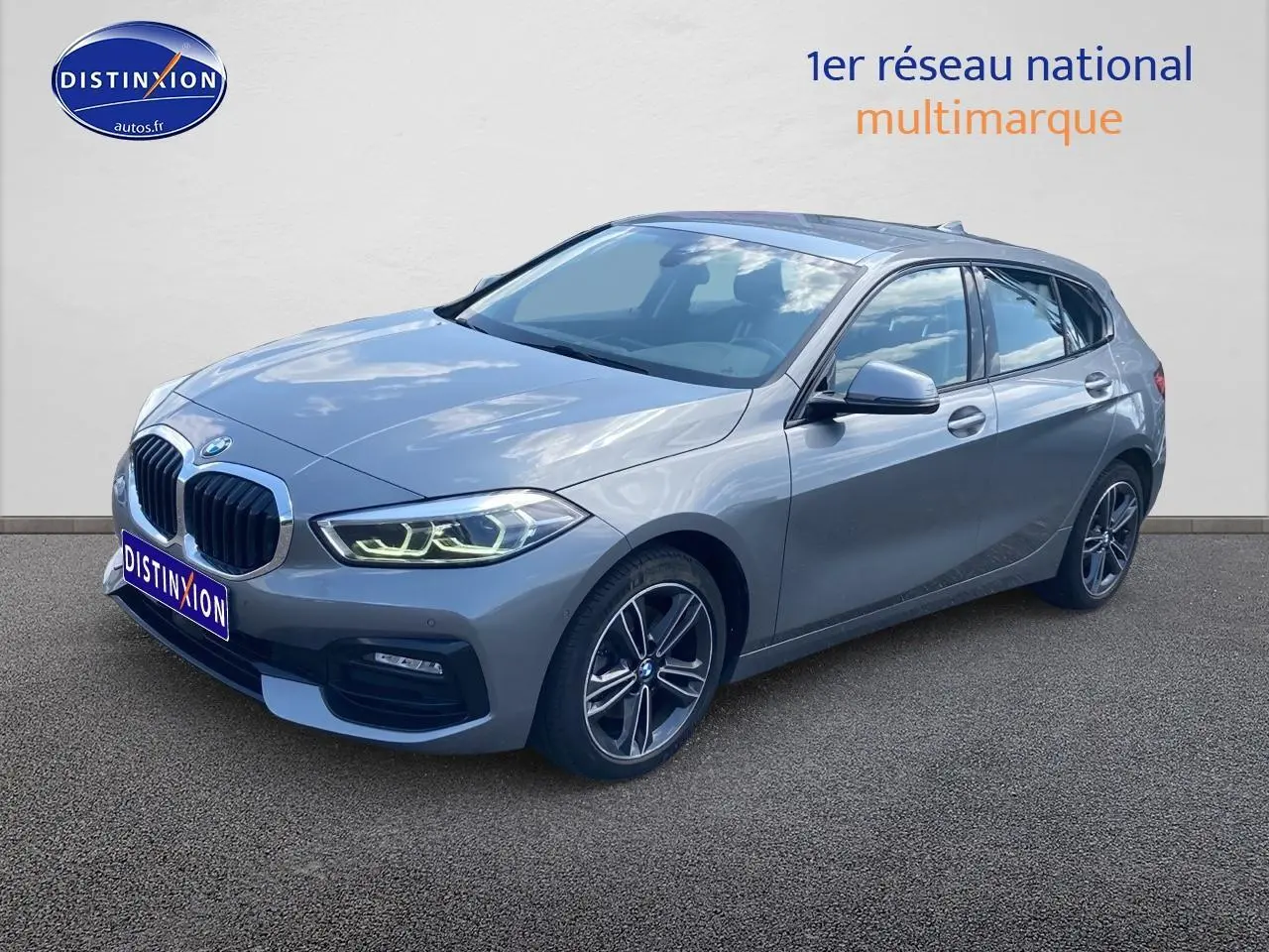 BMW Série 1 gris foncé vue 3/4 avant droit avec phares LED allumés et jantes alliage 17 pouces style 549.