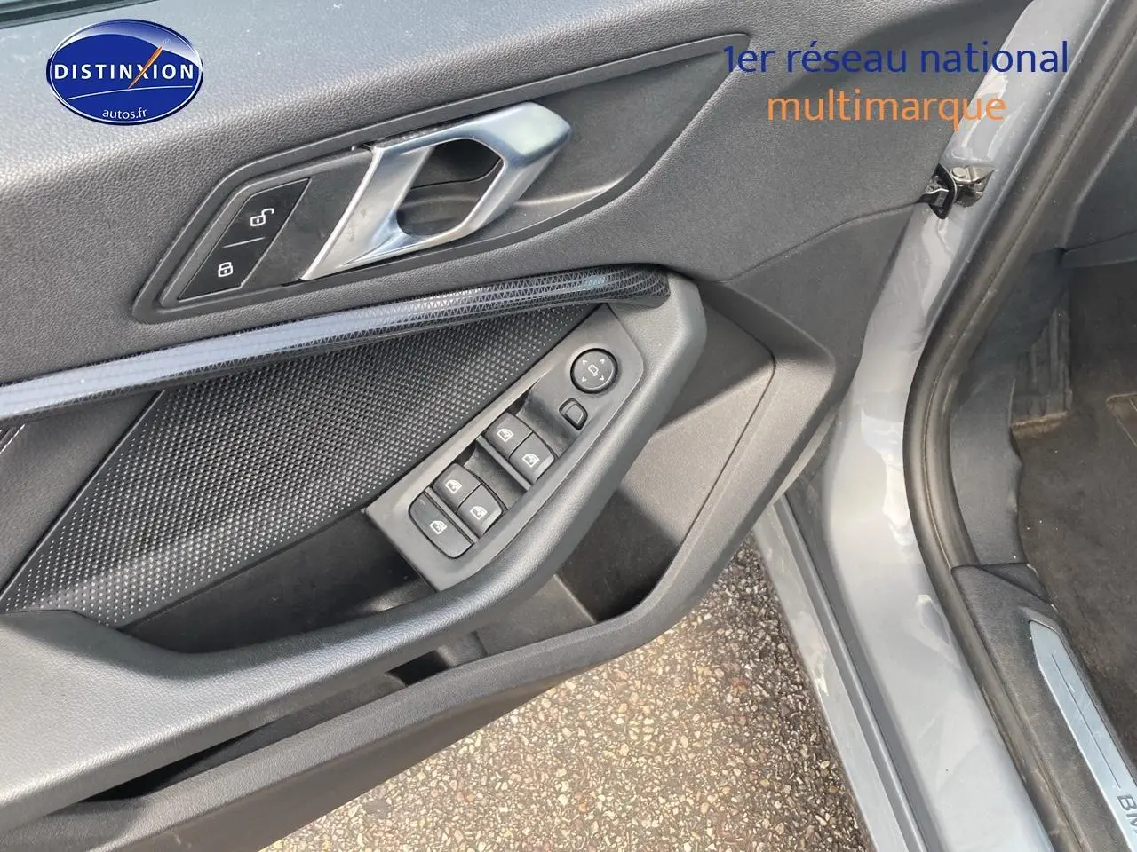 Vue partielle du côté gauche intérieur de la porte d’une BMW Série 1 gris foncé avec commandes de vitres et verrouillage.