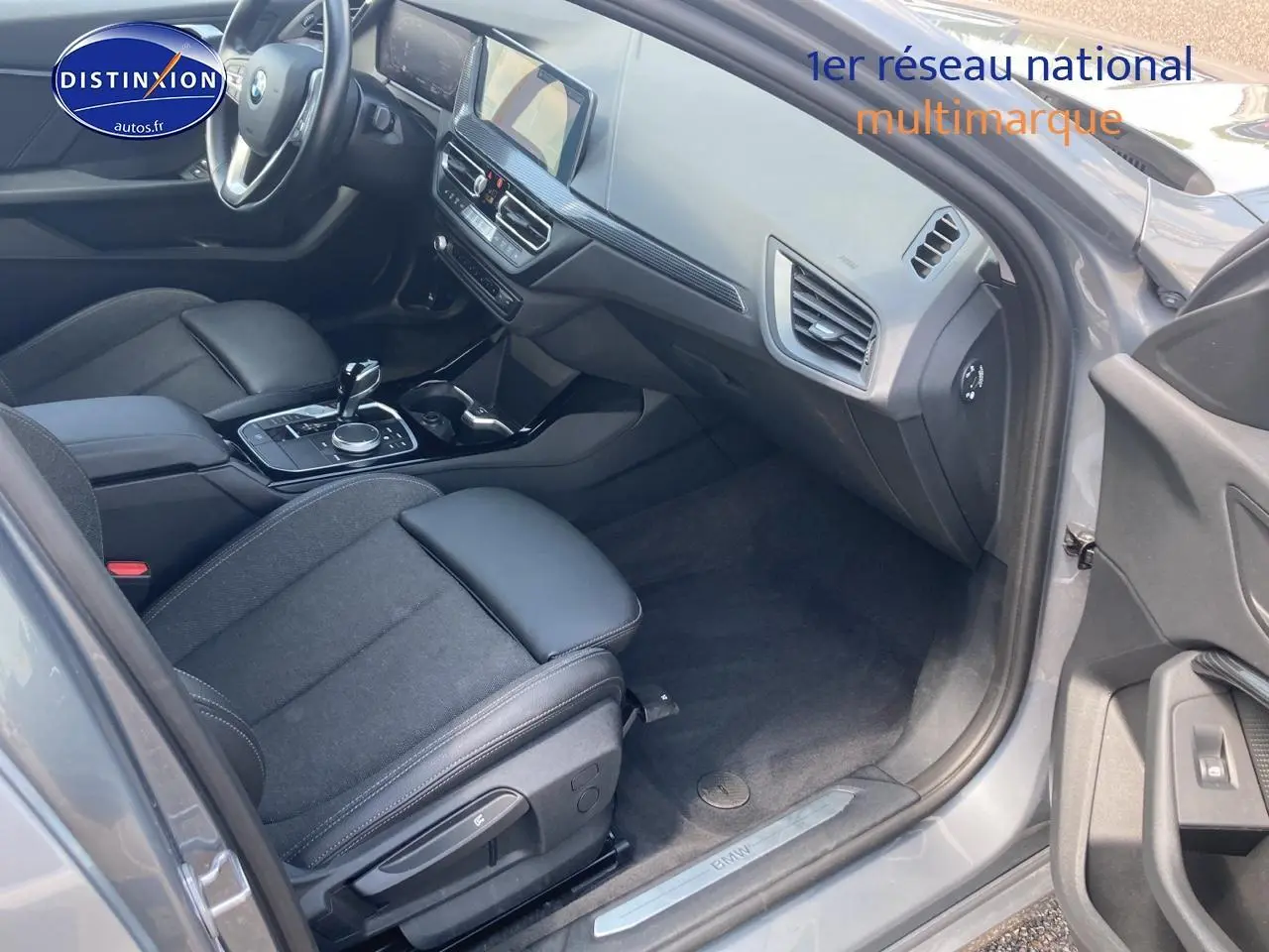 Intérieur côté passager d'une BMW Série 1 gris foncé, mettant en valeur sièges sport et tableau de bord moderne.