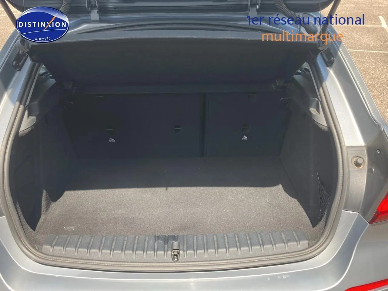Coffre ouvert d'une BMW Série 1 gris foncé, vue arrière montrant l'espace de chargement vide.
